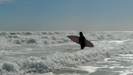 Mujer-Con-Tabla-De-Surf-Parada-En-El-Mar-4k