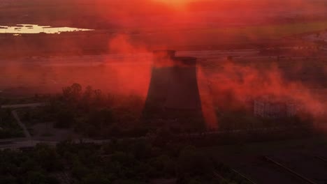 Industrial-smokestacks-surrounded-by-smoke-emissions-illuminated-by-the-orange-sunlight,-high-contrast-close-up-shot