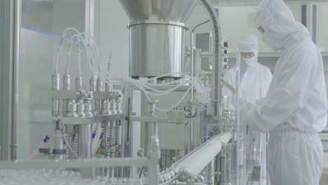 inside pharmaceutical factory manufacturing worker in protective clothing gear operating production line in sterile environment