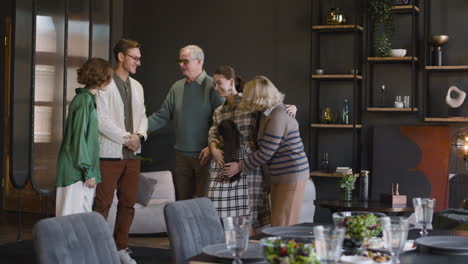 Glückliche-Familie,-Die-Nach-Der-Begrüßung-Am-Tisch-In-Einem-Modernen-Wohnzimmer-Sitzt