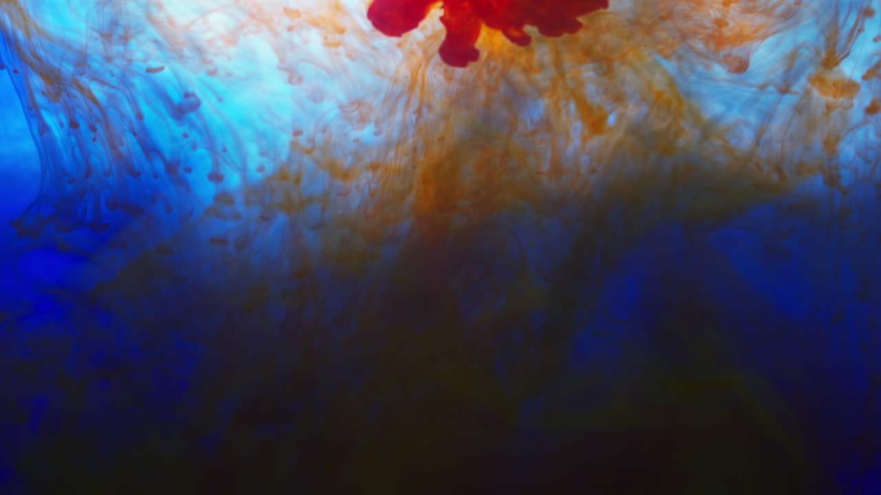 pintura o tinte naranja y azul caído en el agua contra un fondo blanco para crear un fondo de humo de colores giratorios