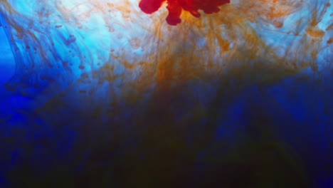 pintura o tinte naranja y azul caído en el agua contra un fondo blanco para crear un fondo de humo de colores giratorios