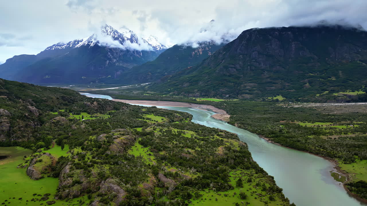 Vista aerea da drone di un fiume tortuoso circondato da verdi vallate e spettacolari cime innevate in Patagonia