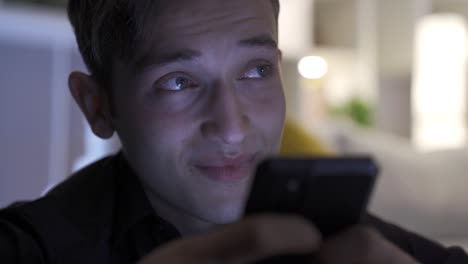 Hand-of-man-texting,-using-smartphone-in-living-room-at-home.