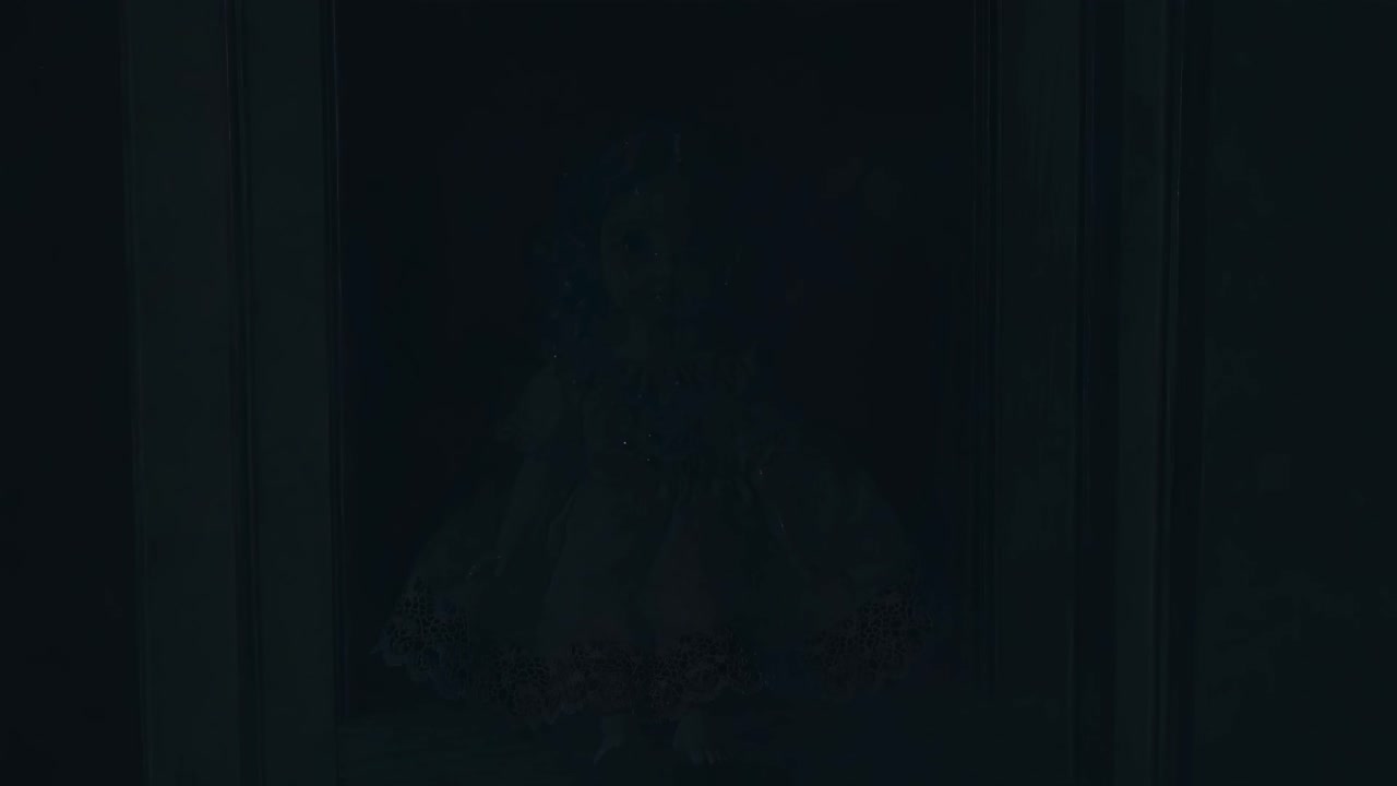 A vintage doll with curly hair in a lace dress sits in a wooden frame