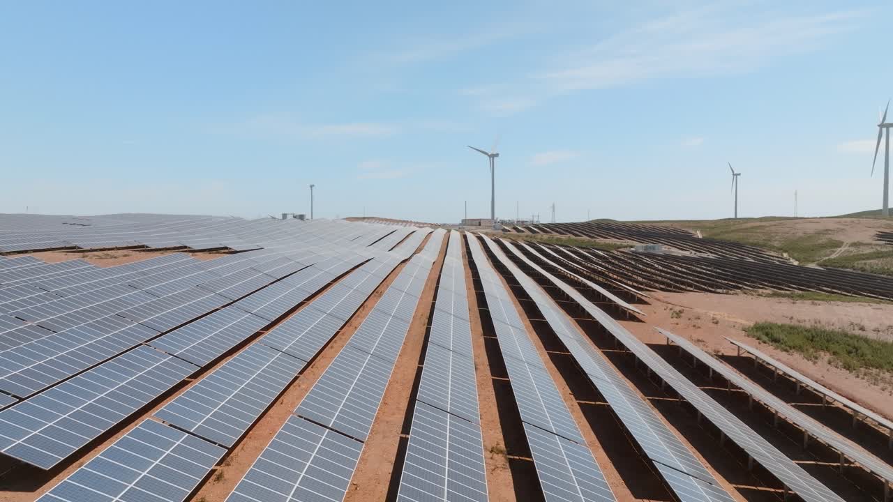 Solar panels in farm wrap along desert hill landscape in organized rows