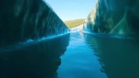 turquoise water fills the frame as a kayak enters a cave, sunlight reflecting on the water's surface