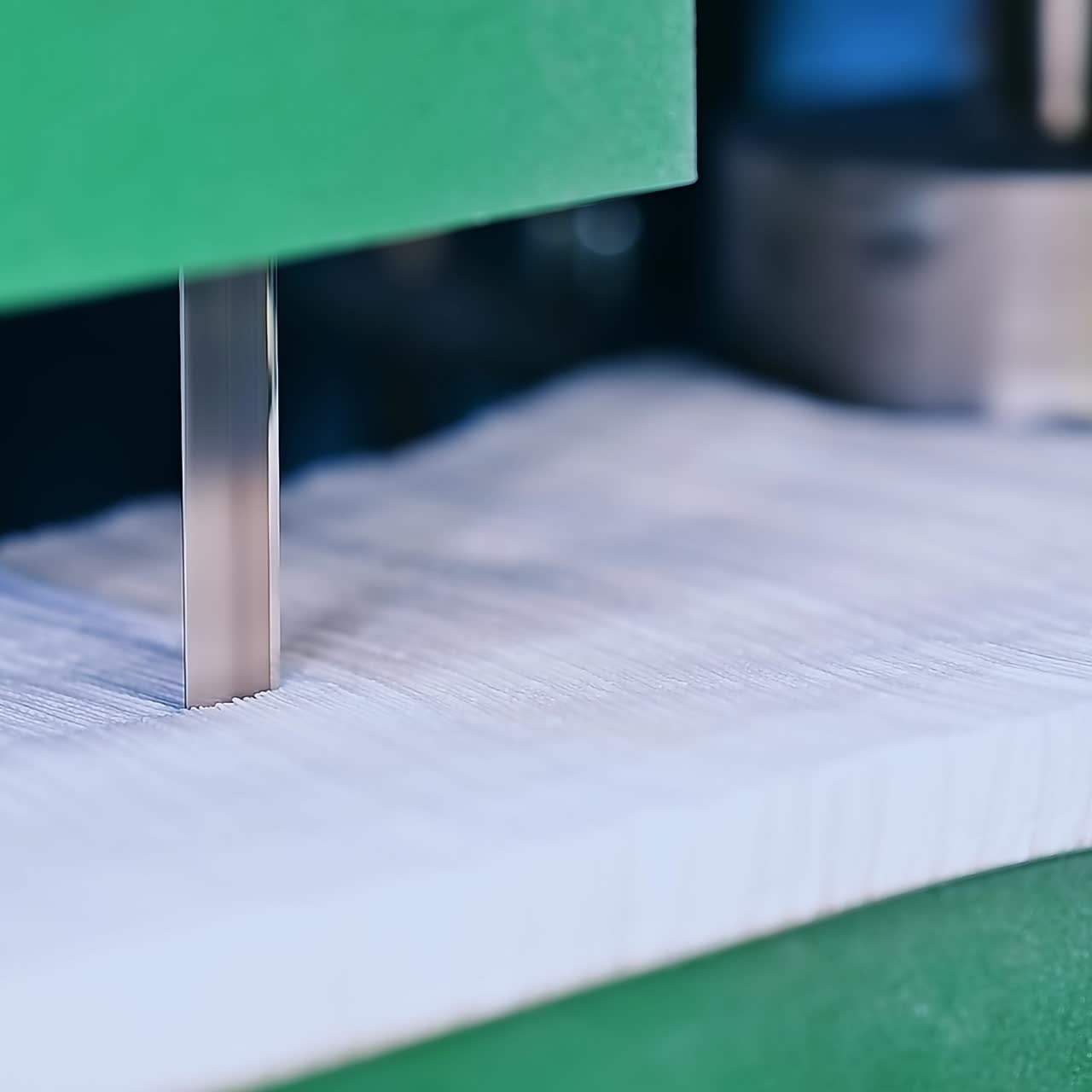 Sharp knife of the cutting mechanism that divides a pile of fabric into two stacks. Two heavy vertical shafts spinning at the backdrop