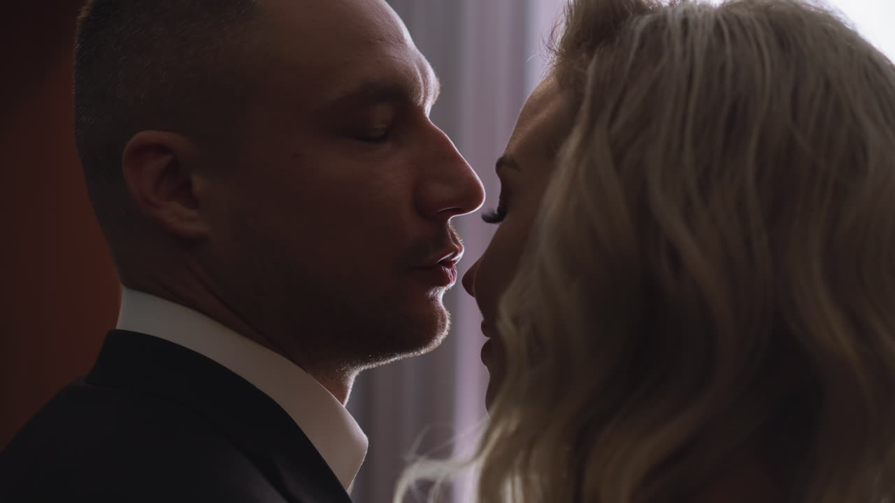 Boyfriend kisses nose of blonde beloved lady in hotel room