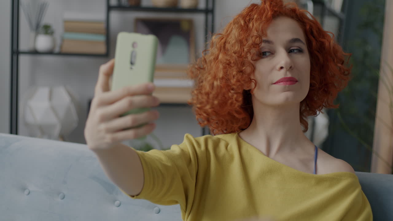 una mujer tomando una selfie en el sofá.