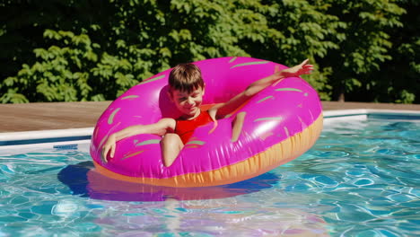 a child floating in a pink donut inflatable in a swimming pool