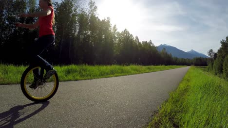 Woman-riding-unicycle-on-countryside-road-4k