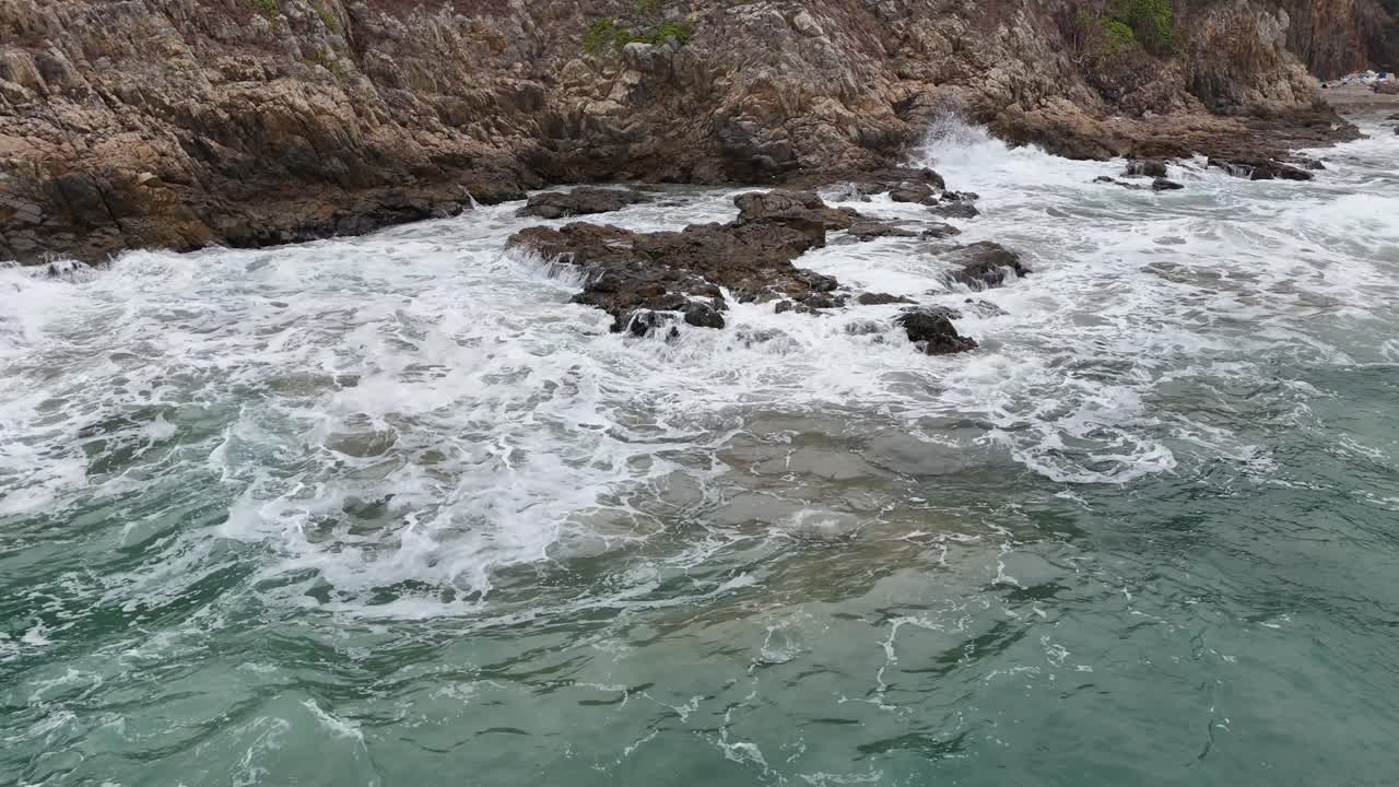 Filmato di potenti onde oceaniche che si infrangono su pietre nere, catturando la schiuma delle onde, gli schizzi d'acqua e il movimento costiero energico per progetti cinematografici o naturalistici.