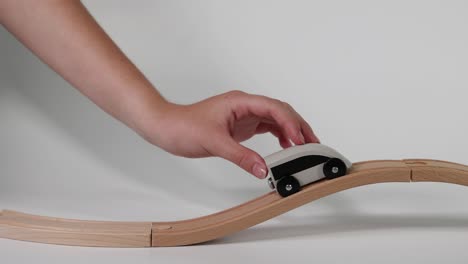 hand guiding toy car on wooden track