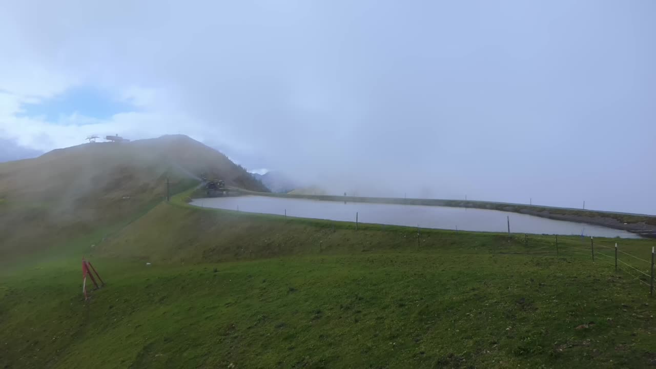 la niebla se desplaza sobre un pequeño y hermoso embalse en la montaña asitz kogel en austria, leogang saalbach