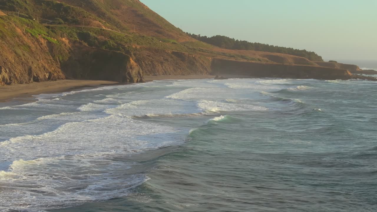 Golden sunlight on the California coast with waves and cliffs