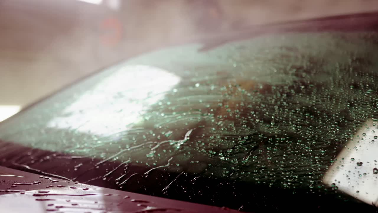 Spraying water washing off car windshield