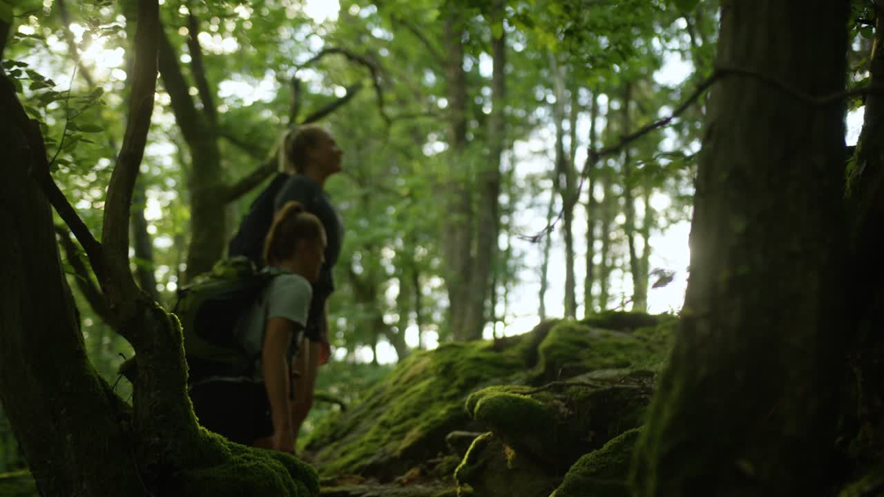 Two women hiking in the mountains with backpacks. Girls on a hike breathing fresh air oxygen. Back to nature
