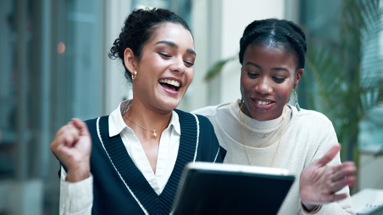 Two women celebrating good news on a tablet