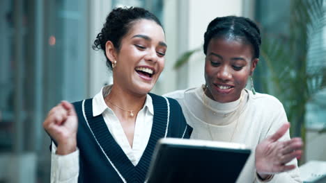 two women celebrating good news on a tablet