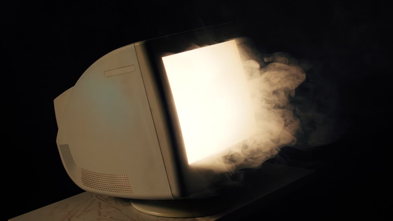 Retro CRT monitor glows brightly, releasing smoke in a dark moody setting, surreal tech malfunction