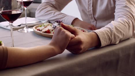 couple holding hands during dinner