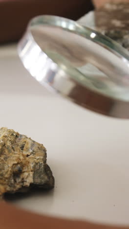 school kids using magnifying glass over rock