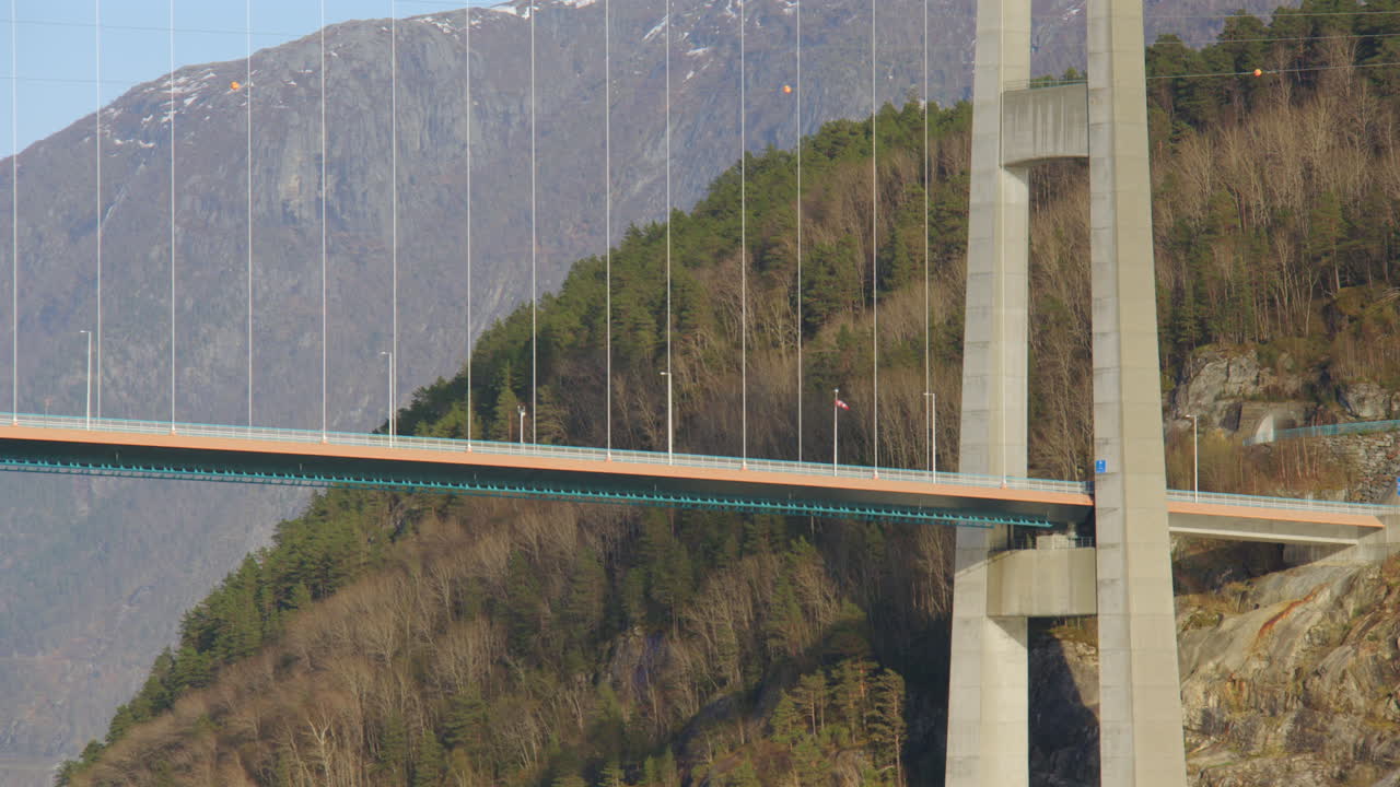 Mid shot of sailing past the Hardanger bridge with cars. on the Eidfjorden, Eldfjord