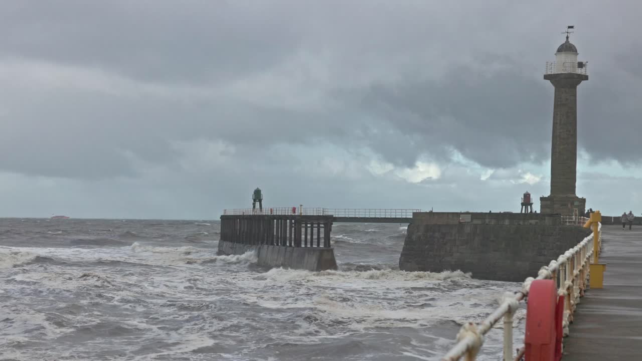 wide angle shot of waves crashing along the walls at Whitby Harbour lighthouse