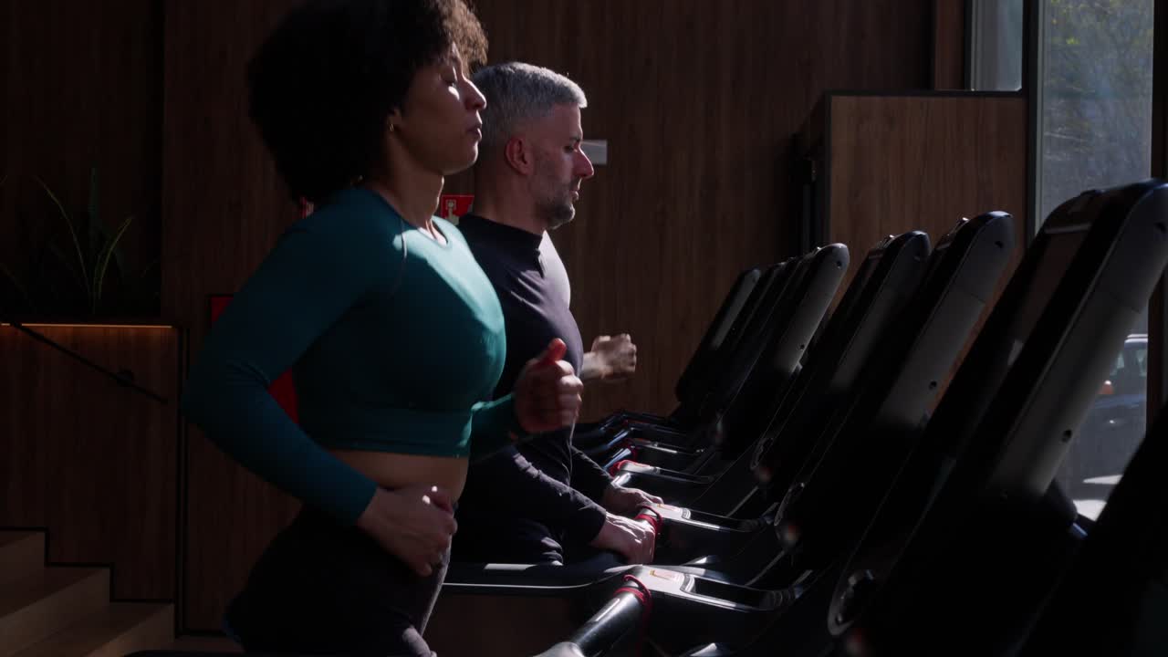 Uomo e donna che corrono su tapis roulant in una palestra moderna