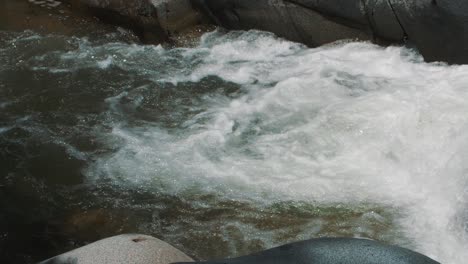 Slow-Motion-shot-of-foamy-water-flowing-in-a-river-in-the-middle-of-the-jungle