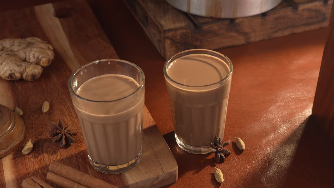 Chai indiano servito in tazze di vetro, preparato in una teiera di metallo con masala aromatici