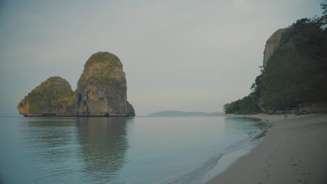 calm sea waters on remote beach at railway with cliff in background