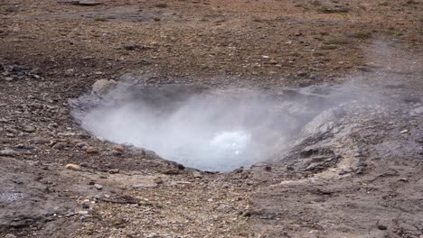 steaming geothermal vent in rocky icelandic terrain with visible water eruption