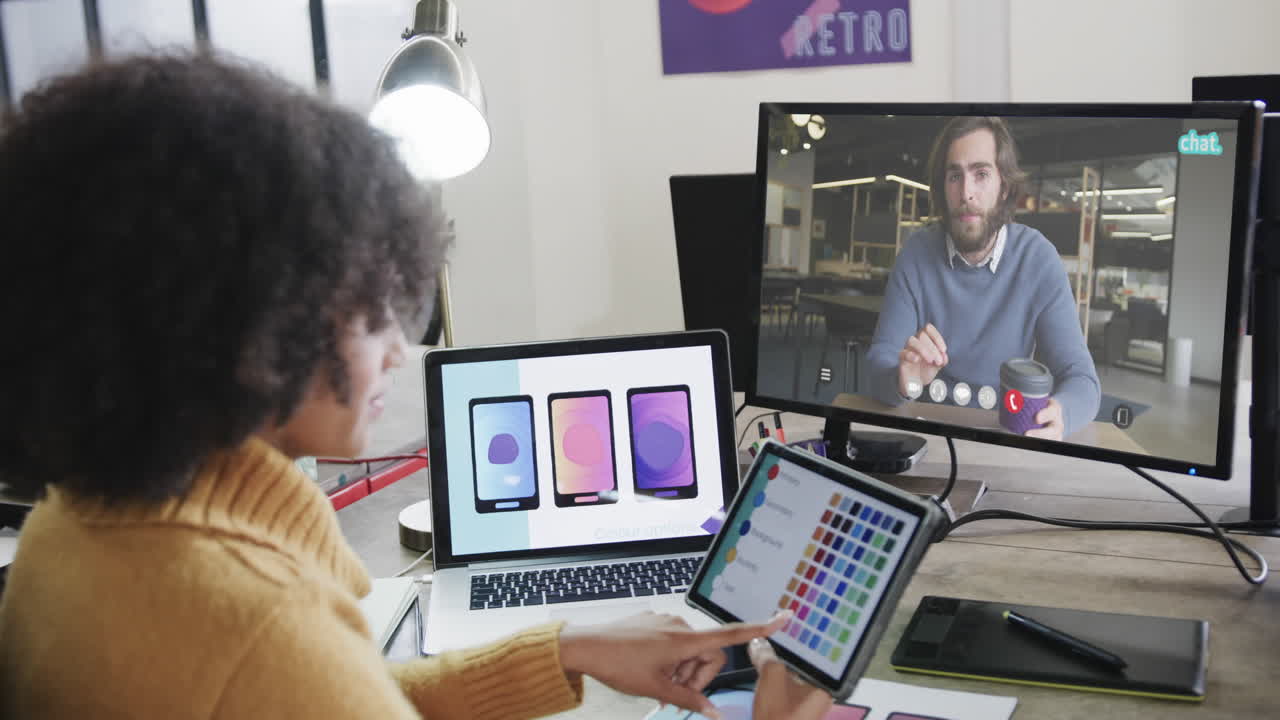 mujer de negocios afroamericana en videollamada con un colega caucásico en la pantalla
