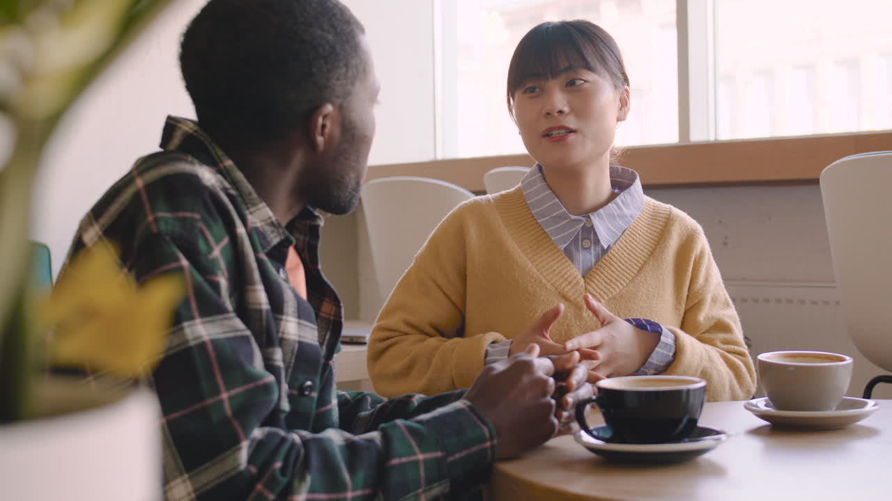Man And Woman Talking Together And Drinking Cappuccino While Sitting At Table In A Coffee Shop 1