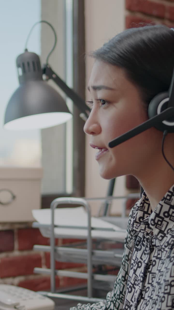 Asiatisk forretningskvinne med headset som jobber i kundesenter
