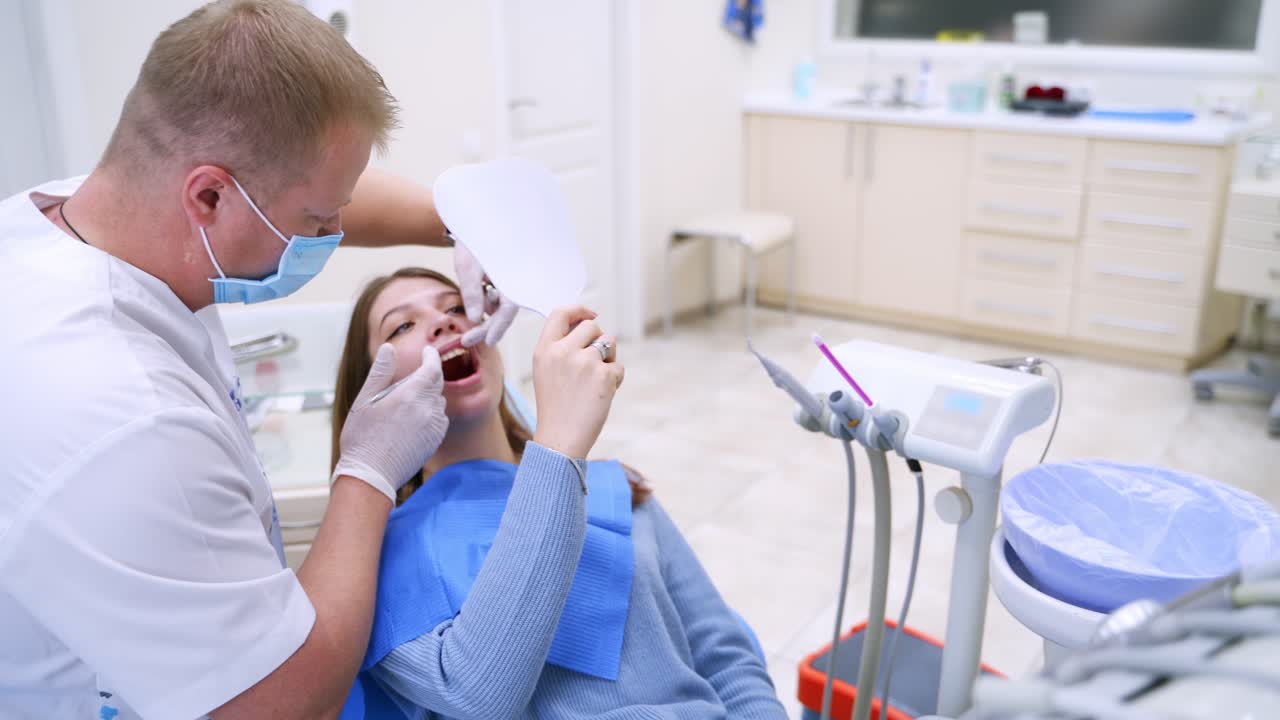 Dental procedure in clinic. Dentist examines the patient teeth at dental chair with open mouth