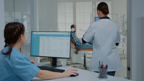 enfermera de estomatología sentada en el escritorio trabajando en la computadora