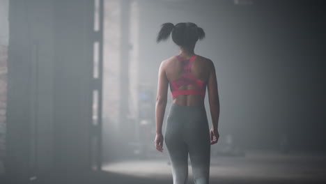 fit woman walking in loft building. tired athlete coming back on start position