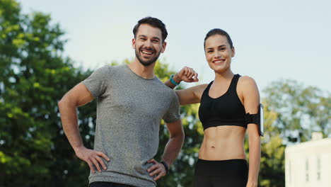 young jogger couple talking and smiling to the camera after sport and jogging in the stadium