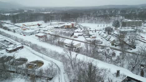 aerial pan across snow covered filtration plant and business distrct next to railroad tracks