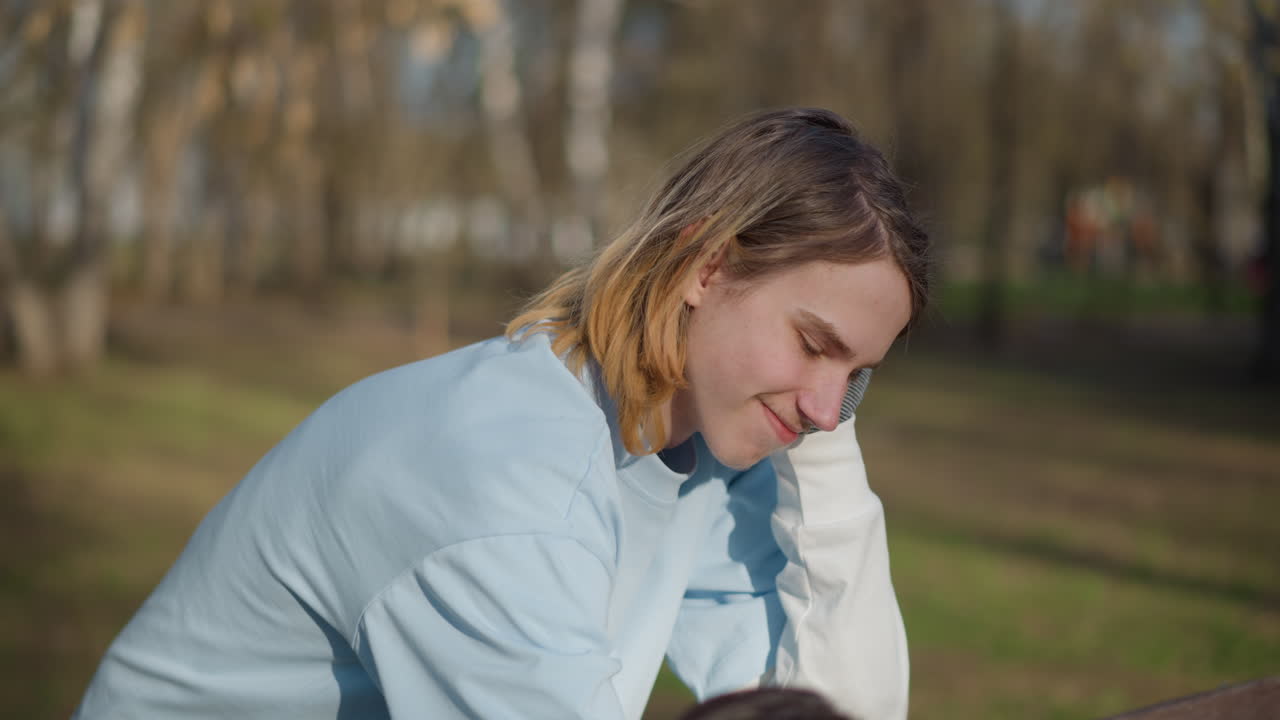 정다운 공원에서의 만남, 어린 남성이 작은 강아지에게 친절을 베푸는 모습, 소년들과 애완견 사이의 우정을 보여주는 편안한 장면, 햇볕이 잘 드는 공원에서 10대 소년들이 다정한 동료애를 나누는 순간