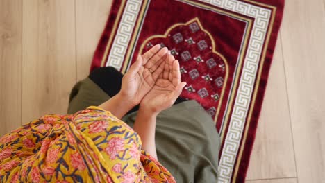 una mujer musulmana orando en una alfombra de oración