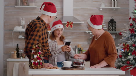 Abuelos-Con-Nieto-Usando-Gorro-De-Papá-Noel-Saludando-A-Amigos-Remotos-Durante-Una-Videollamada-En-Línea