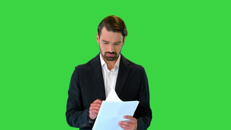 joven hombre de negocios serio leyendo documentos mientras camina en una pantalla verde, clave de croma