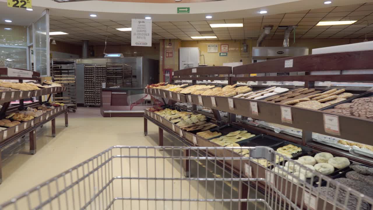 Close-up of a person walking through a supermarket with a shopping cart