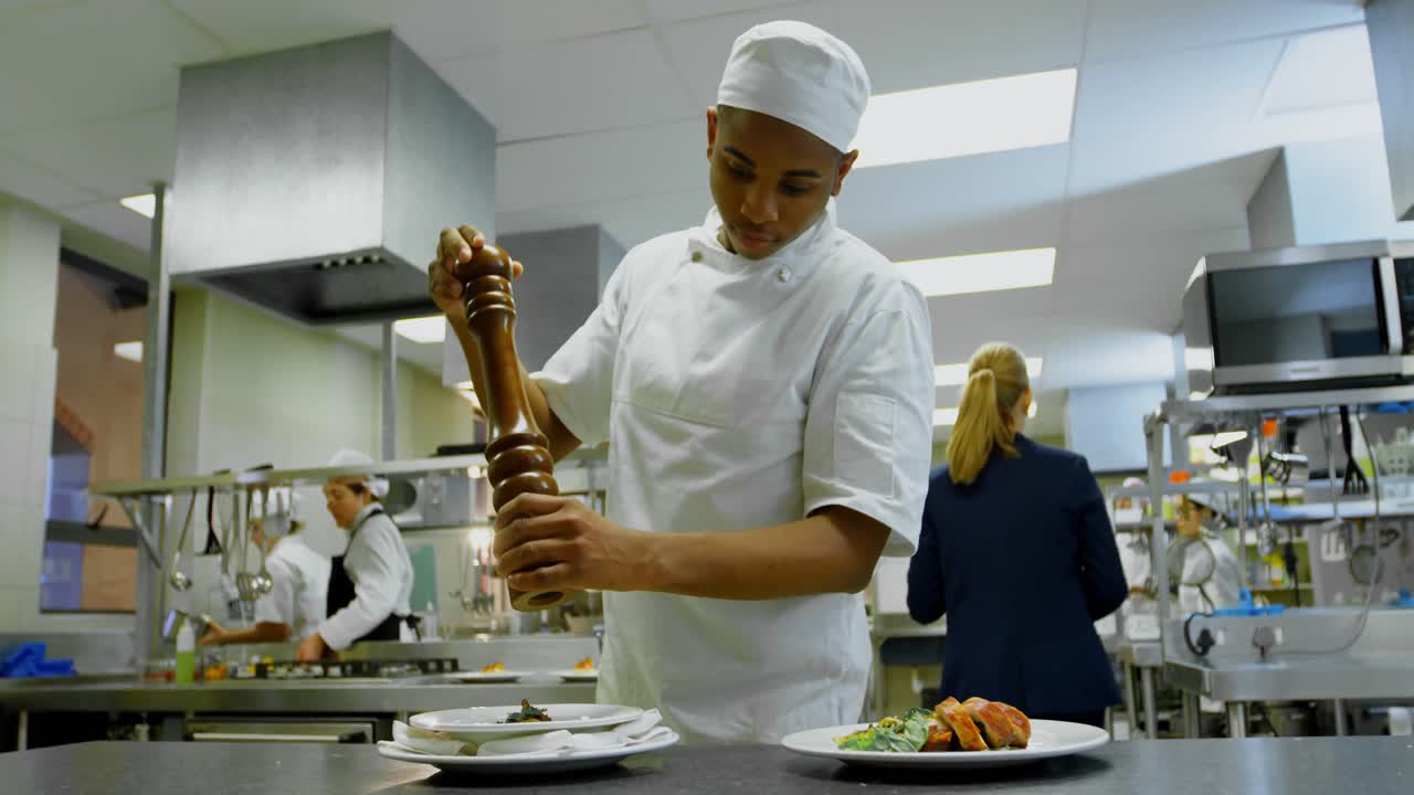 chef usando molino de pimienta en la cocina en el restaurante 4k