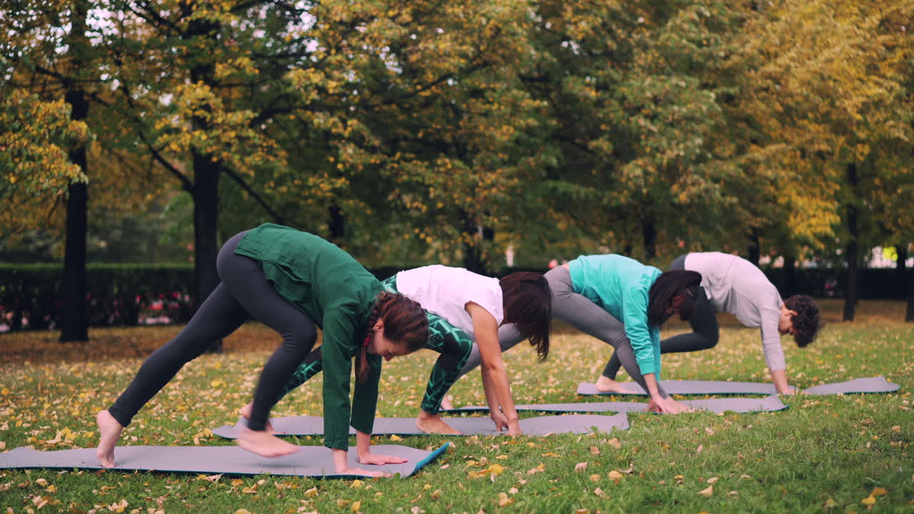 Women practicing yoga outdoors in autumn park