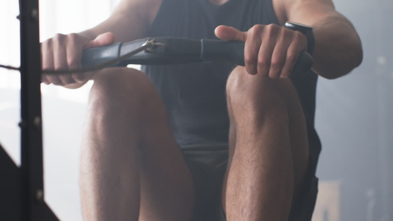 Using rowing machine, man exercising in gym, focusing on fitness and strength